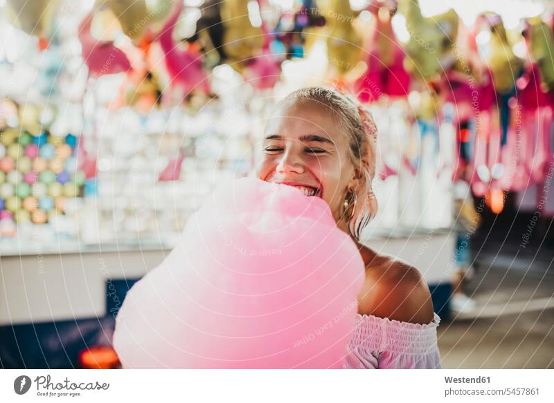 Close-up of smiling young woman with eyes closed holding cotton candy at amusement park 20-25 years 20 to 25 years young women one person only one person 1