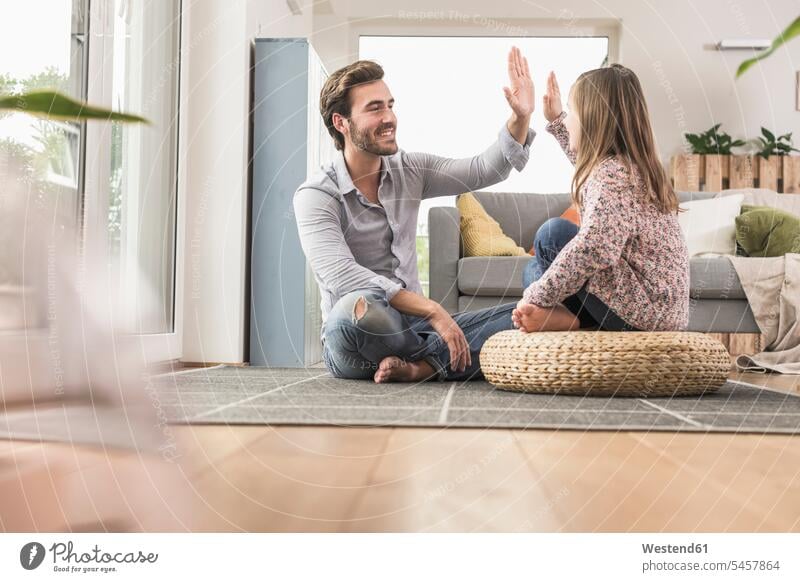 Young man and little girl sitting at home, giving high five optimistic optimism sitting on ground Sitting On The Floor Sitting On Floor full length full-length