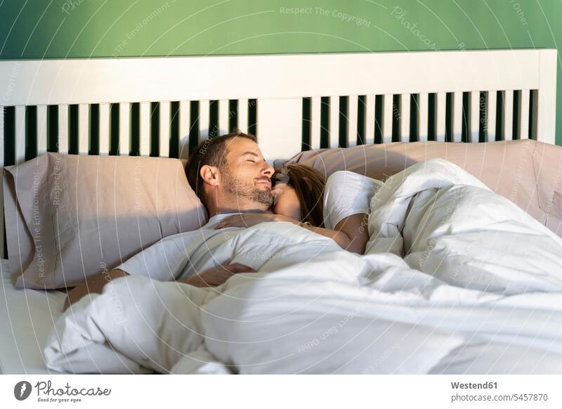 Woman embracing man while sleeping on bed at home color image colour image indoors indoor shot indoor shots interior interior view Interiors morning