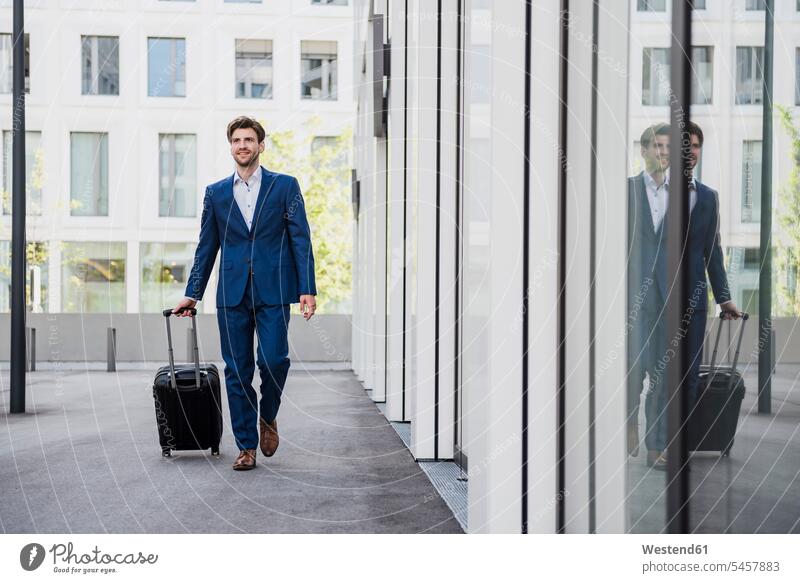 Smiling businessman with baggage in the city on the move smiling smile town cities towns Businessman Business man Businessmen Business men on the way on the go