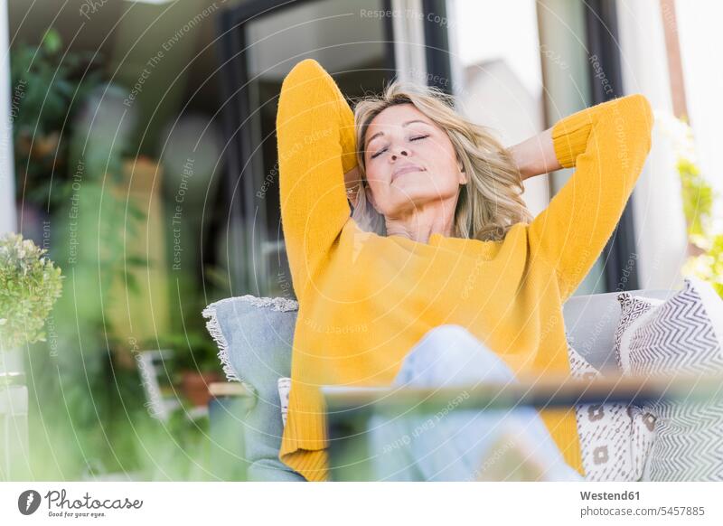 Portrait of mature woman with eyes closed relaxing on terrace jumper sweater Sweaters chairs Arm Chair Arm Chairs armchairs Seated sit enjoy enjoyment