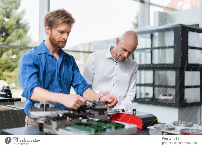 Two men working on product in company firm products attention attentive paying attention Cooperation working together collaboration Cooperating Cooperate