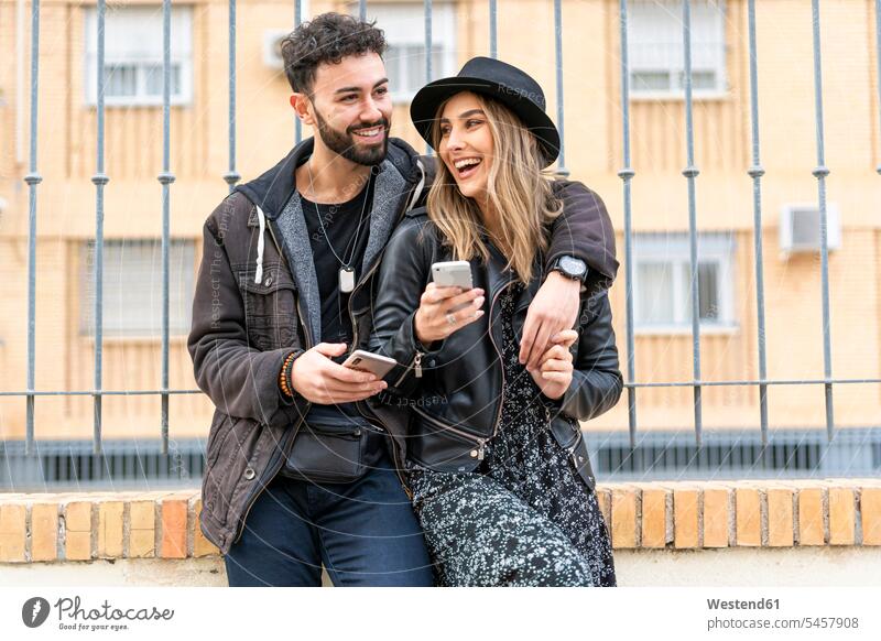 Portrait of laughing young couple with their mobile phones in the city human human being human beings humans person persons caucasian appearance