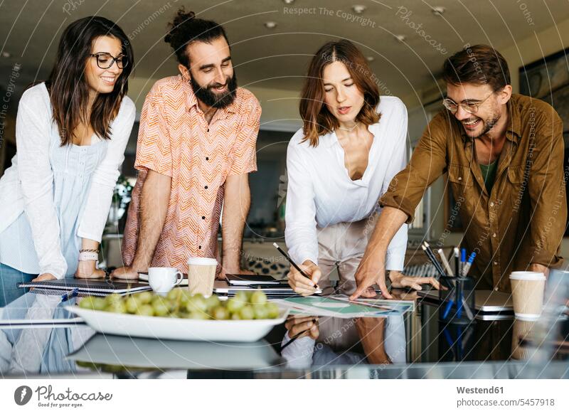 Happy friends working together on table at home human human being human beings humans person persons caucasian appearance caucasian ethnicity european