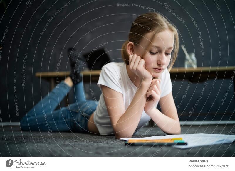 Girl lying on carpet and learning at home pencil pencils pens carpets rug rugs read floors indoor indoor shot indoor shots interior interior view Interiors