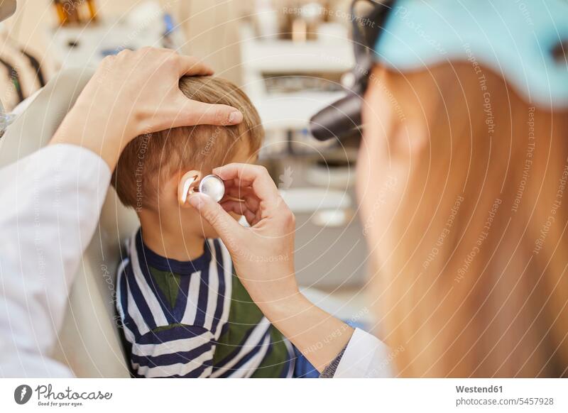 ENT physician examining ear of a boy ears Female Doctor physicians Female Doctors boys males checking examine people persons human being humans human beings