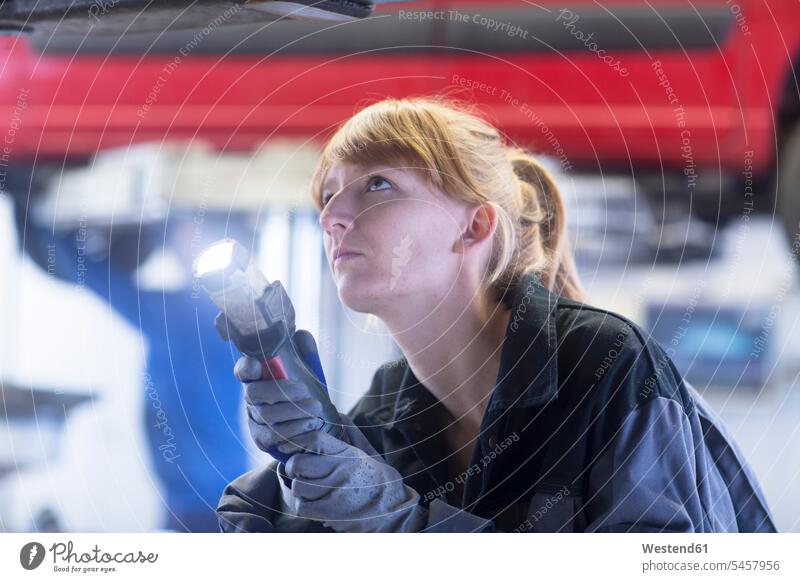 Female car mechanic with lamp looking to bottom of a car in repair garage Gritty Gritty Woman strong woman strong women crafts hand work handcraft handicraft