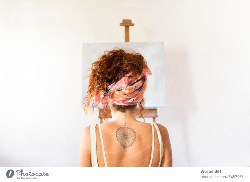 Rear view of young female painter in art studio in front of empty canvas Spain female artist female artists curly curly hair curls curled nonconformity blank