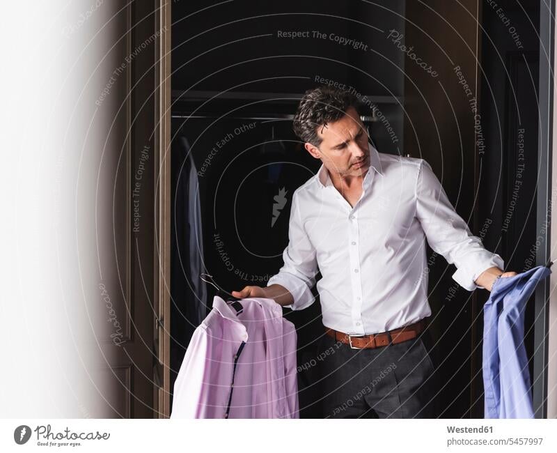 Businessman at home getting dressed choosing shirt from wardrobe wardrobes armoire Business man Businessmen Business men shirts dressing select choose selecting