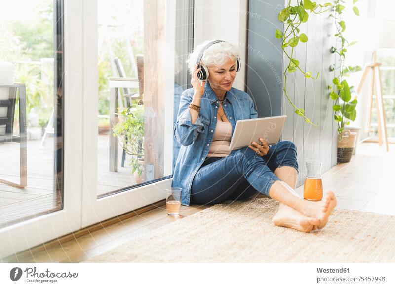 Mature woman listening to music while working on digital tablet color image colour image indoors indoor shot indoor shots interior interior view Interiors day