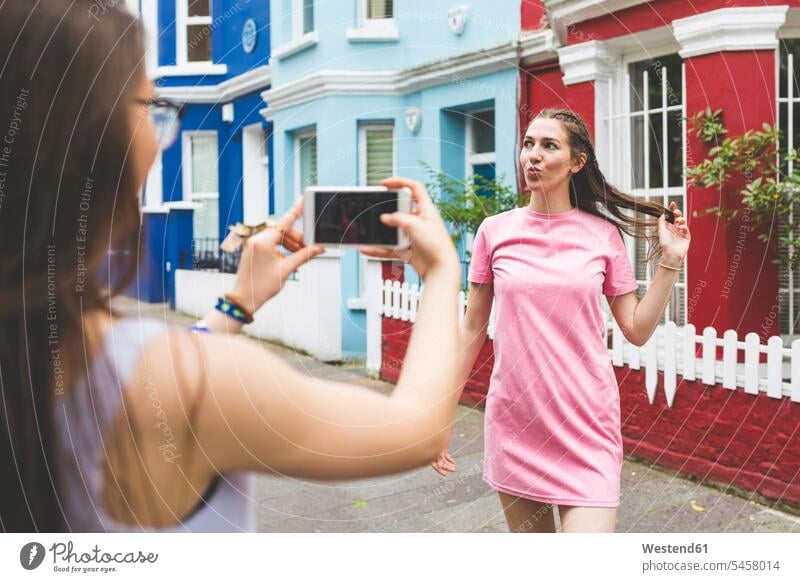 Teenage girl taking cell phone picture of young woman in the city mobile phone mobiles mobile phones Cellphone cell phones Teenage Girls female teenagers