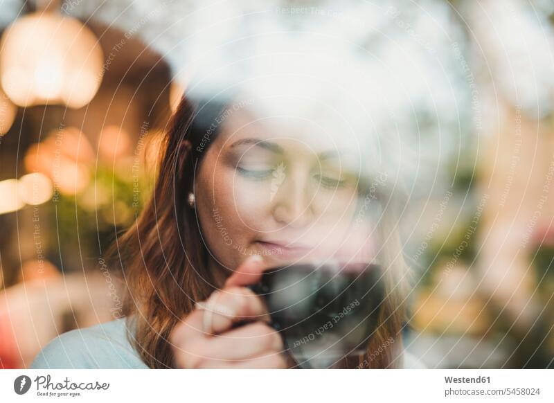 Young woman in a cafe drinking coffee behind windowpane human human being human beings humans person persons caucasian appearance caucasian ethnicity european