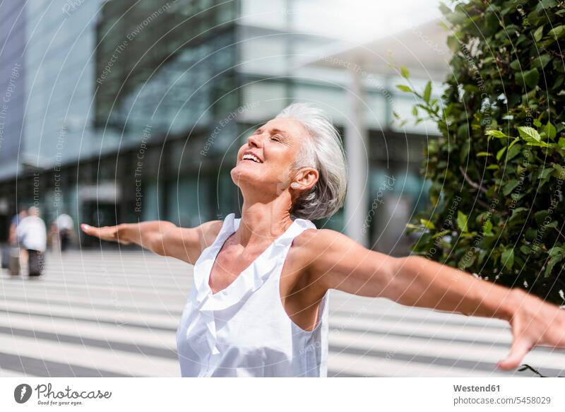Happy senior woman with outstretched arms in the city happiness happy senior women elder women elder woman old town cities towns females senior adults Adults
