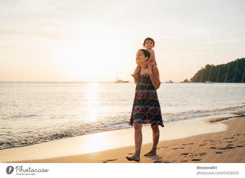 Thailand, Krabi, Koh Lanta, Mother with little daughter on her shoulders on the beach at sunset mother mommy mothers ma mummy mama Trust Confidence Faith