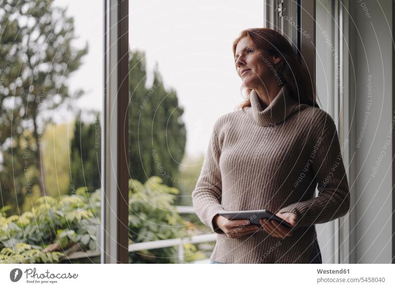 Woman looking out of window, holding digital tablet human human being human beings humans person persons caucasian appearance caucasian ethnicity european 1