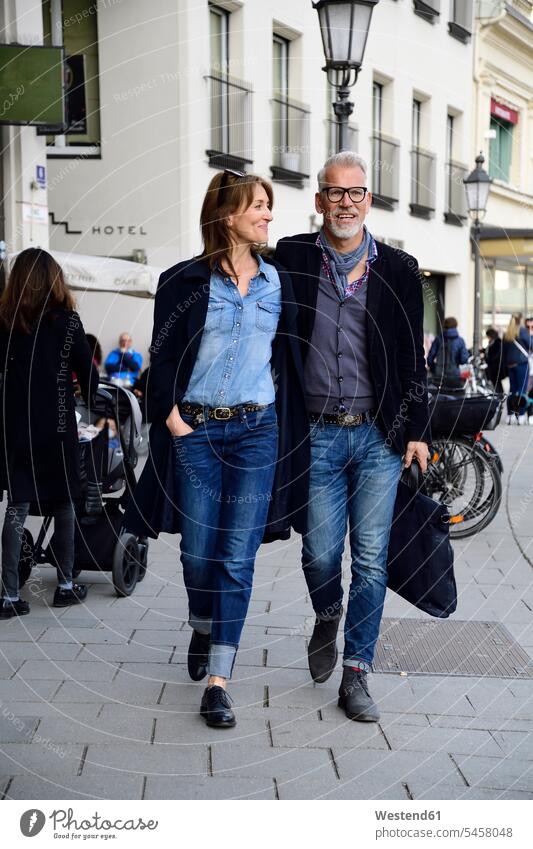 Mature couple walking in the city, with arms around bags go going buy shop smile delight enjoyment Pleasant pleasure Cheerfulness exhilaration gaiety gay glad