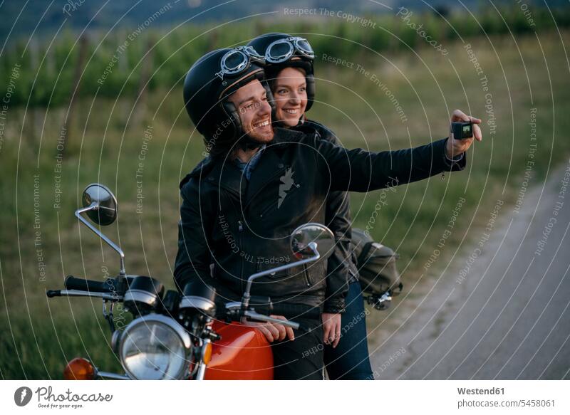 Portrait of happy young couple on vintage motorbike taking a selfie at roadside transport motor vehicles road vehicle road vehicles Motor Cycle motorbikes