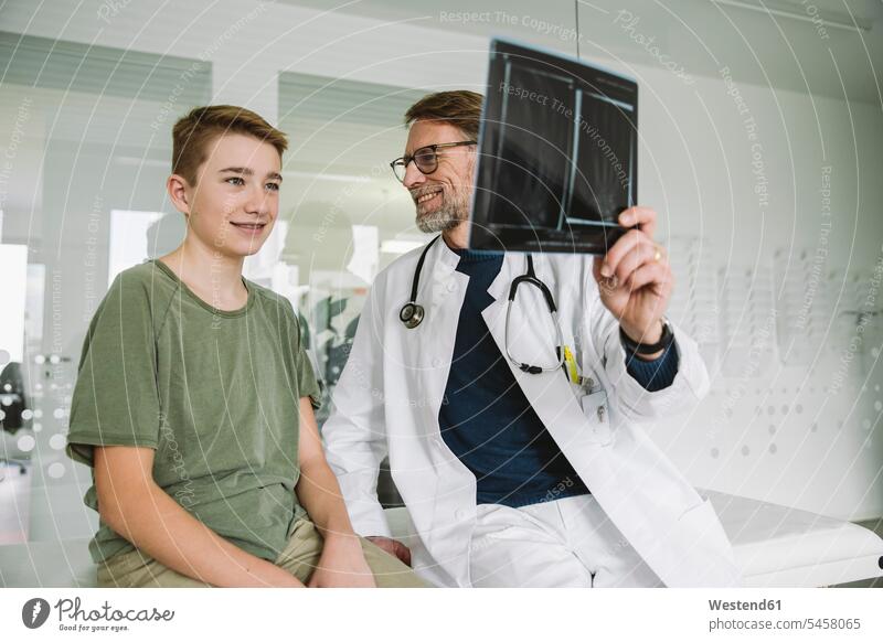 Doctor explaining x-ray image of broken hand to teenage boy in medical practice health healthcare Healthcare And Medicines medicine disease diseases ill