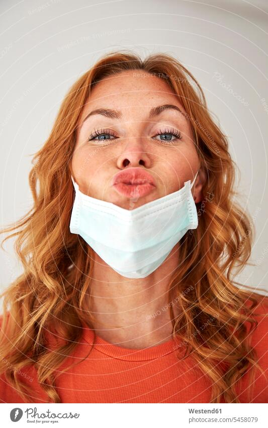 Portrait of red-haired woman with kissing lips over a protective mask human human being human beings humans person persons caucasian appearance