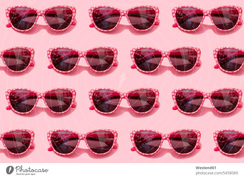 Pattern of pink retro sunglasses against pastel pink background studio shot studio photograph studio photographs studio shots indoors indoor shot indoor shots