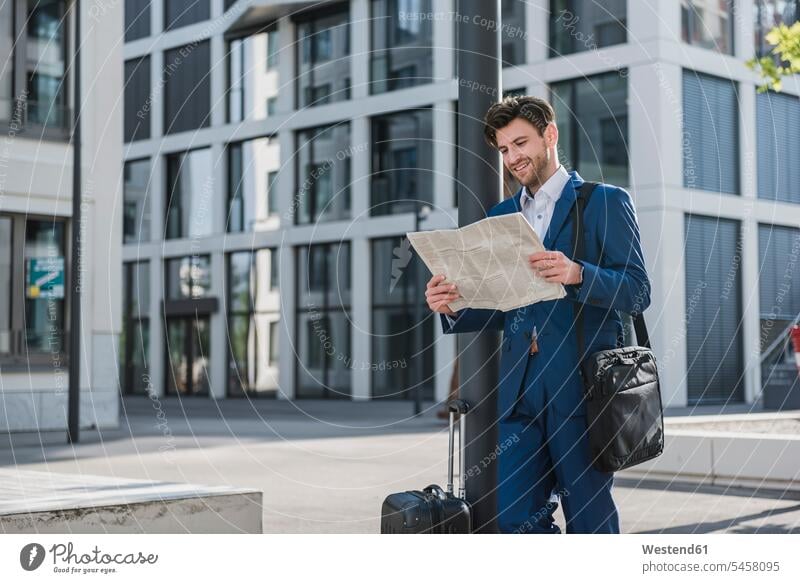 Smiling businessman with baggage reading newspaper in the city Businessman Business man Businessmen Business men smiling smile newspapers town cities towns