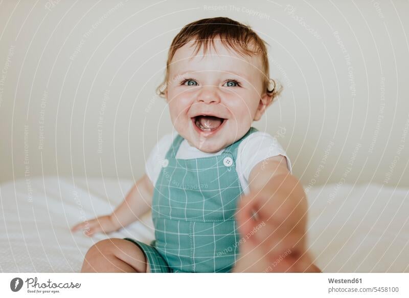 Close-up of baby girl laughing while sitting on bed at home color image colour image Spain leisure activity leisure activities free time leisure time indoors