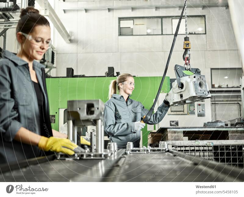 Two woman working on a machine workwear working clothes male profession Cooperation working together collaboration Cooperating Cooperate Co-Operation