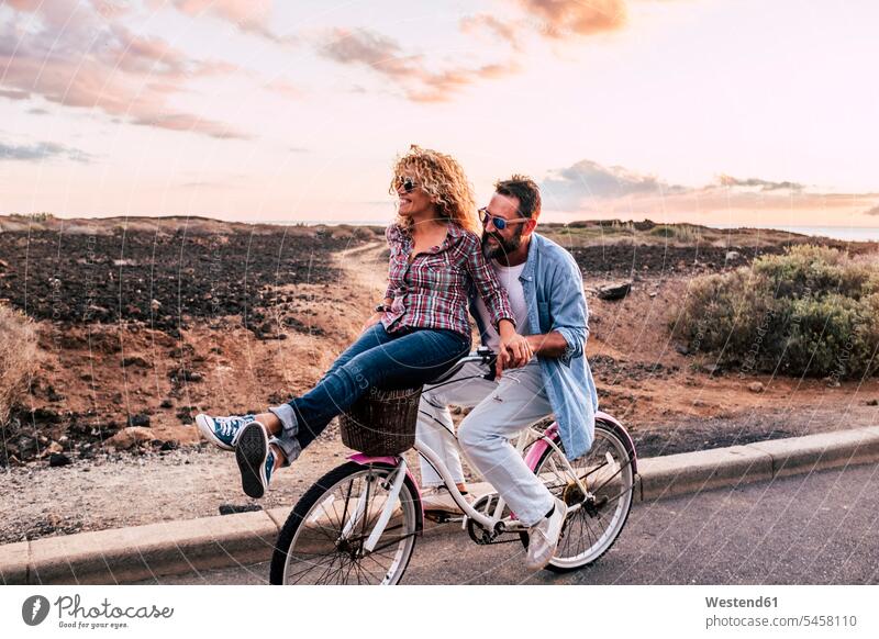 Smiling couple on bicycle, Tenerife, Spain bikes bicycles Cycle Cycle - Vehicle Eye Glasses Eyeglasses specs spectacles Pair Of Sunglasses sun glasses smile