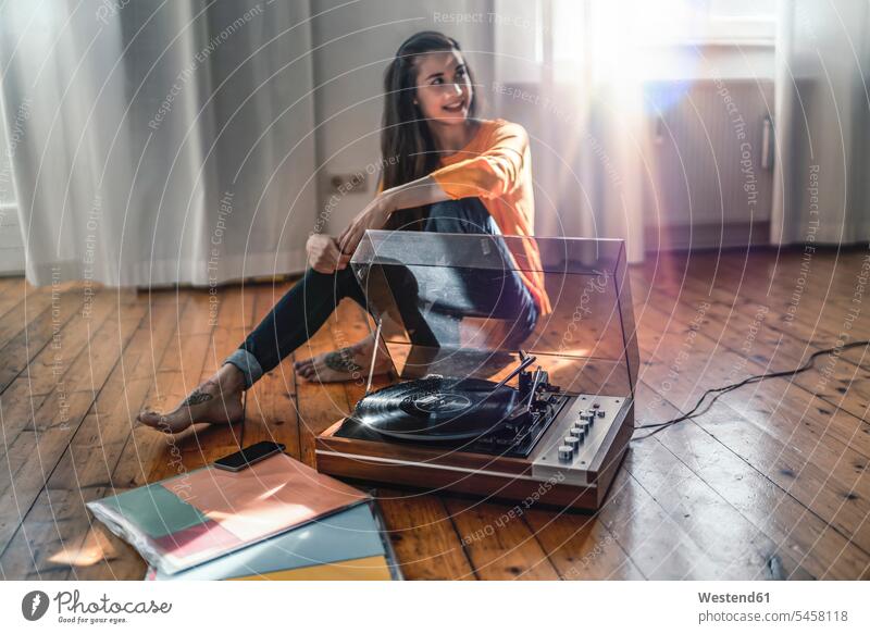 Young woman sitting on the floor at home with a record player human human being human beings humans person persons Mixed Race mixed race ethnicity