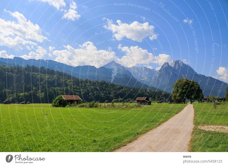 Field path near Garmisch-Partenkirchen with view to the Zugspitz massif on a sunny day with blue sky and white cumulus clouds Germany View alp copy space