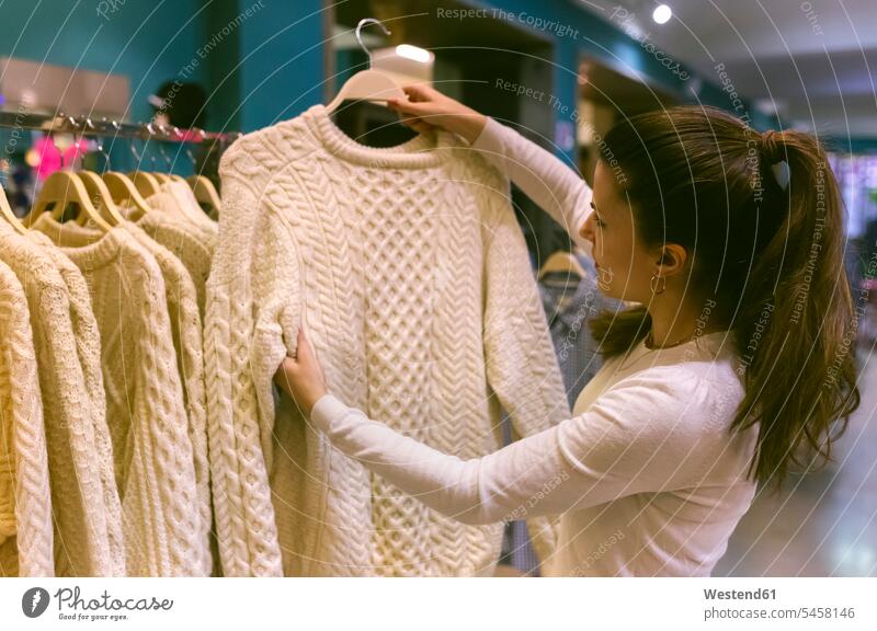Woman holding a pullover in a vintage boutique clothes Apparel boutiques shop woman females women shopping sweater jumper Sweaters stores shops retail trade