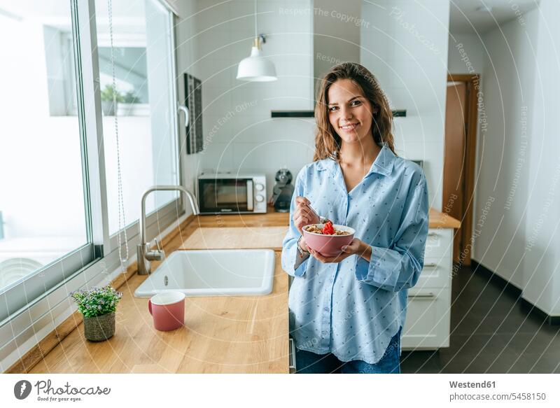Portrait of young woman wearing pyjama eating muesli in kitchen at home human human being human beings humans person persons celibate celibates singles
