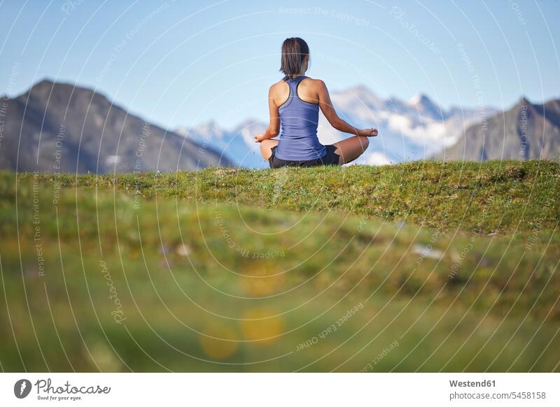 Woman meditating in the mountains, rear view Seated sit sports athletes Sportsman Sportsmen Sportspeople Sportsperson free Liberty peaceful peacefulness