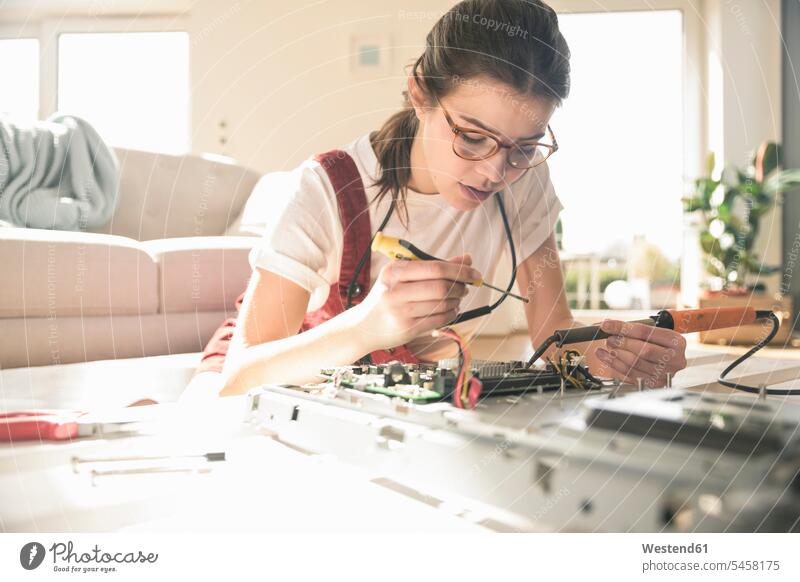 Young woman working on computer equipment at home Germany soldering Printed Circuit Board Competence Skill attention attentive paying attention mounting