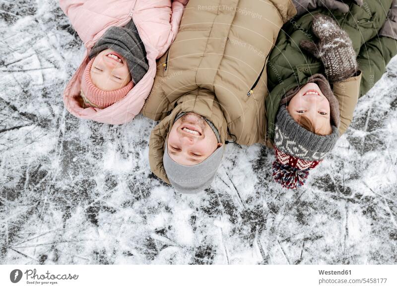 Family portrait of father and two children lying on ice in winter human human being human beings humans person persons caucasian appearance caucasian ethnicity