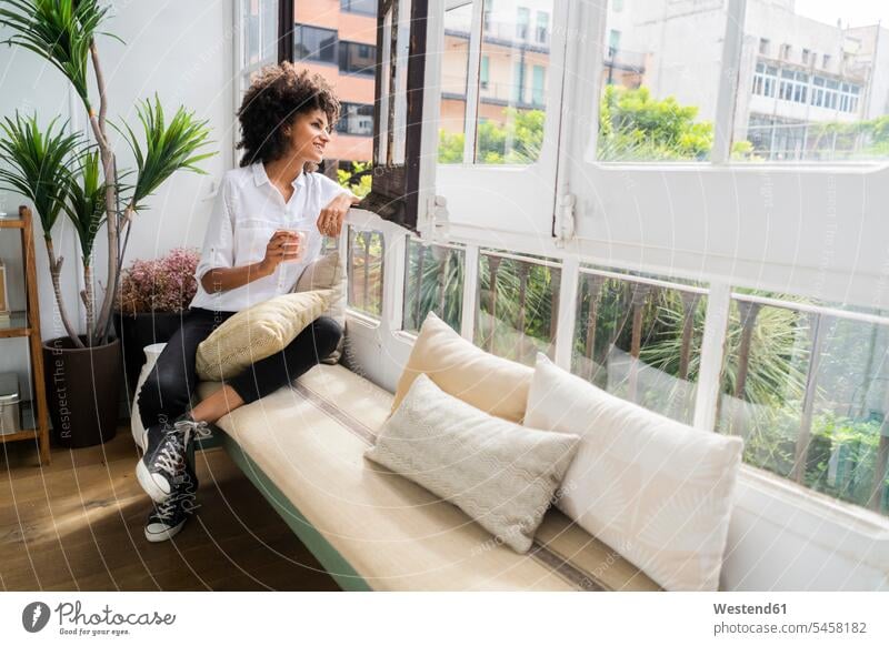 Beautiful woman sitting on bench, looking out of window, drinking coffee windows flat flats apartment apartments Looking Through Window Looking Through A Window