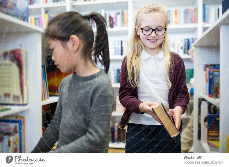 Two schoolgirls in school library schools female pupils School Girl School Girls book books schoolchildren education Knowledge Selective focus