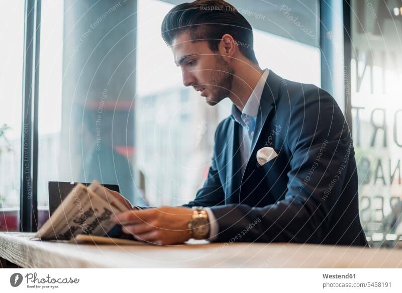 Young businessman reading newspaper in a cafe newspapers Businessman Business man Businessmen Business men business people businesspeople business world