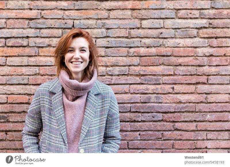 Portrait of a happy young woman standing at a brick wall females women walls brick walls portrait portraits happiness Adults grown-ups grownups adult people