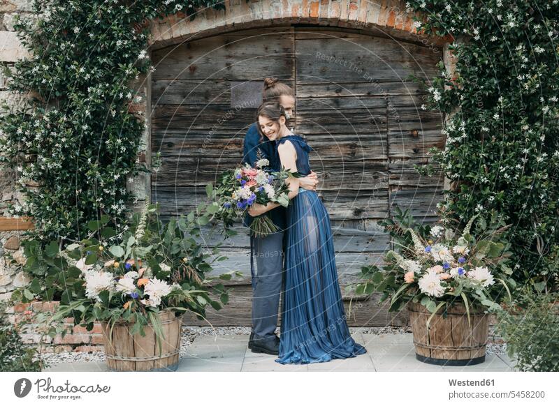 Bride and groom standing at a wooden gate embracing bride brides bridal couple bridal couples bridegrooms gates embrace Embracement hug hugging Wedding