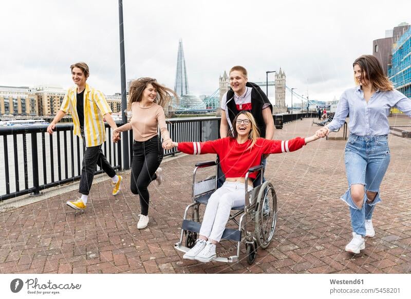 Cheerful men and women with disabled female friend enjoying in city, London, UK color image colour image outdoors location shots outdoor shot outdoor shots day