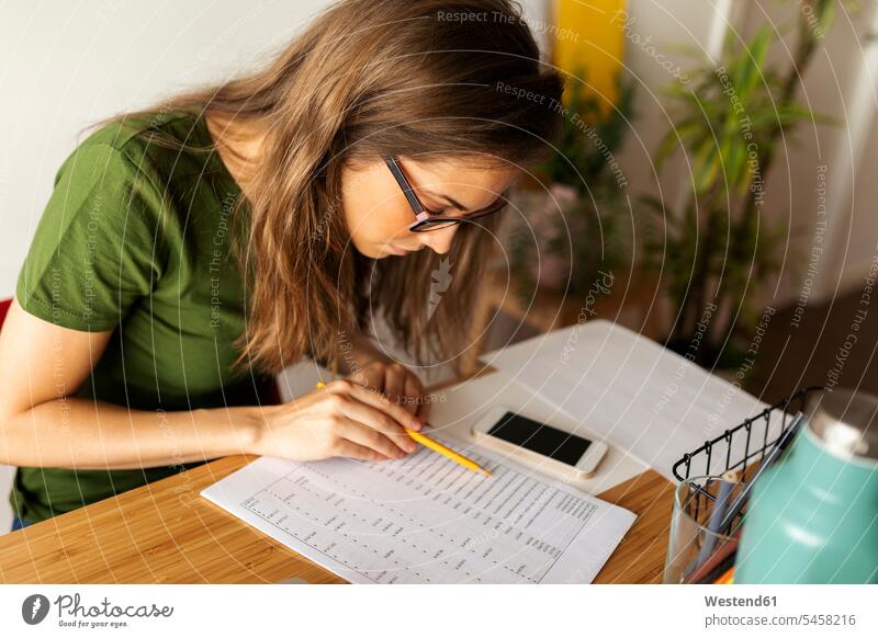 Businesswoman reading document on desk in home office color image colour image Spain casual clothing casual wear leisure wear casual clothes Casual Attire
