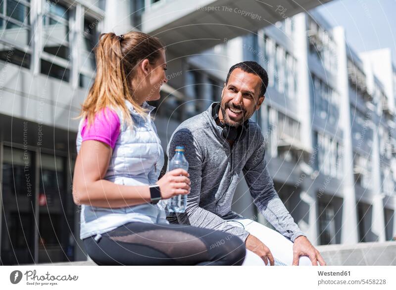Active couple with water bottle having a break in the city water bottles bottled water twosomes partnership couples town cities towns active Bottle Bottles