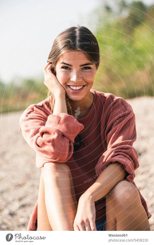 Portrait of smiling young woman sitting outdoors portrait portraits smile Seated females women Adults grown-ups grownups adult people persons human being humans