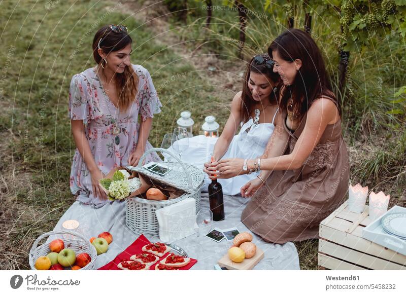 Friends having a summer picnic in vineyard summer time summery summertime drinking Picnic picnicking female friends Meals Food foods food and drink Nutrition