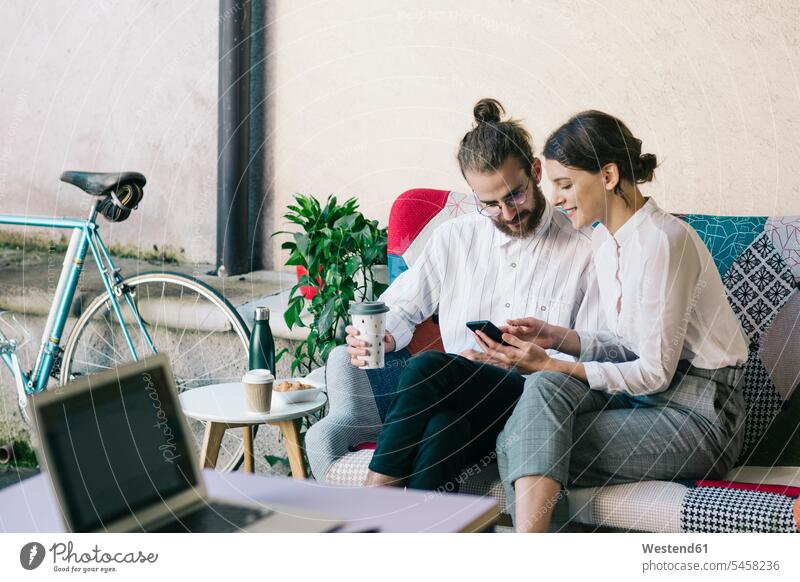 Young couple sitting on a sofa using a smartphone human human being human beings humans person persons caucasian appearance caucasian ethnicity european 2