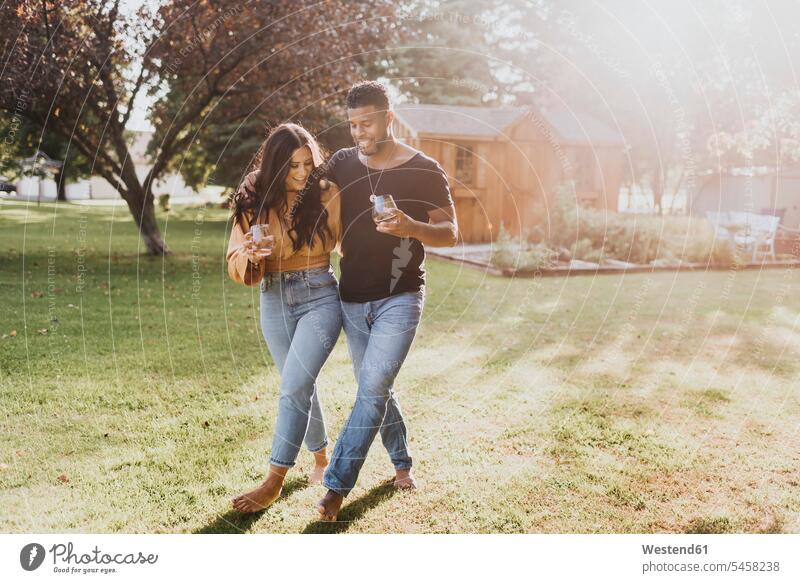 Man and woman holding wineglass while walking at backyard color image colour image outdoors location shots outdoor shot outdoor shots day daylight shot
