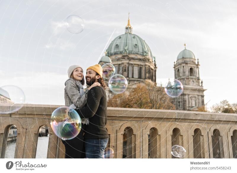 Happy young couple embracing watching soap bubbles in the city, Berlin, Germany human human being human beings humans person persons caucasian appearance