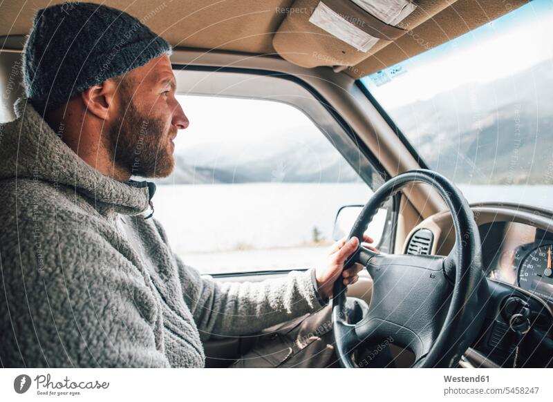 Young man with woolly hat and beard on a road trip Road Trip roadtrip Road-Trip Travel Wooly Hat Knit-Hat Knit Hats wool cap car automobile Auto cars motorcars