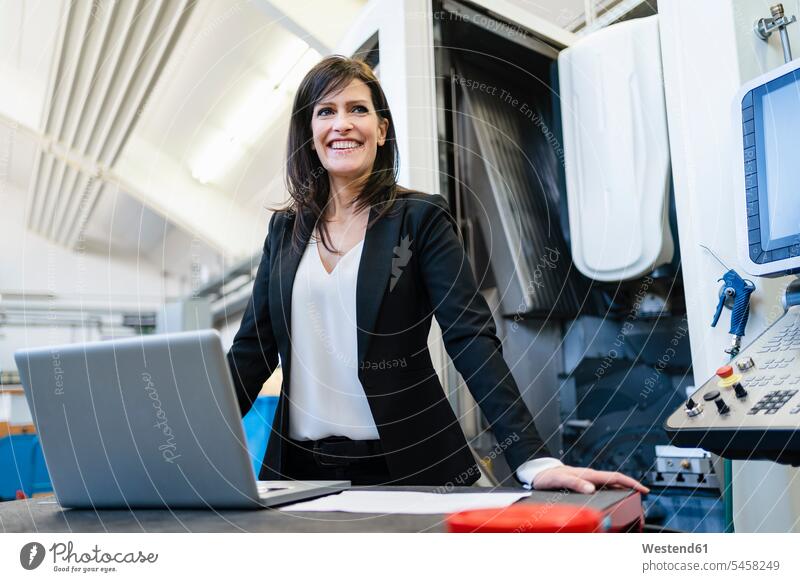 Portrait of happy businesswoman with laptop in a factory human human being human beings humans person persons caucasian appearance caucasian ethnicity european